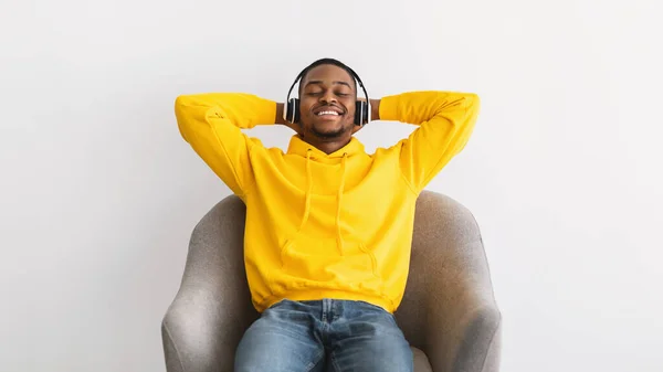 Afro-americano escuchando música usando auriculares, fondo gris —  Fotos de Stock