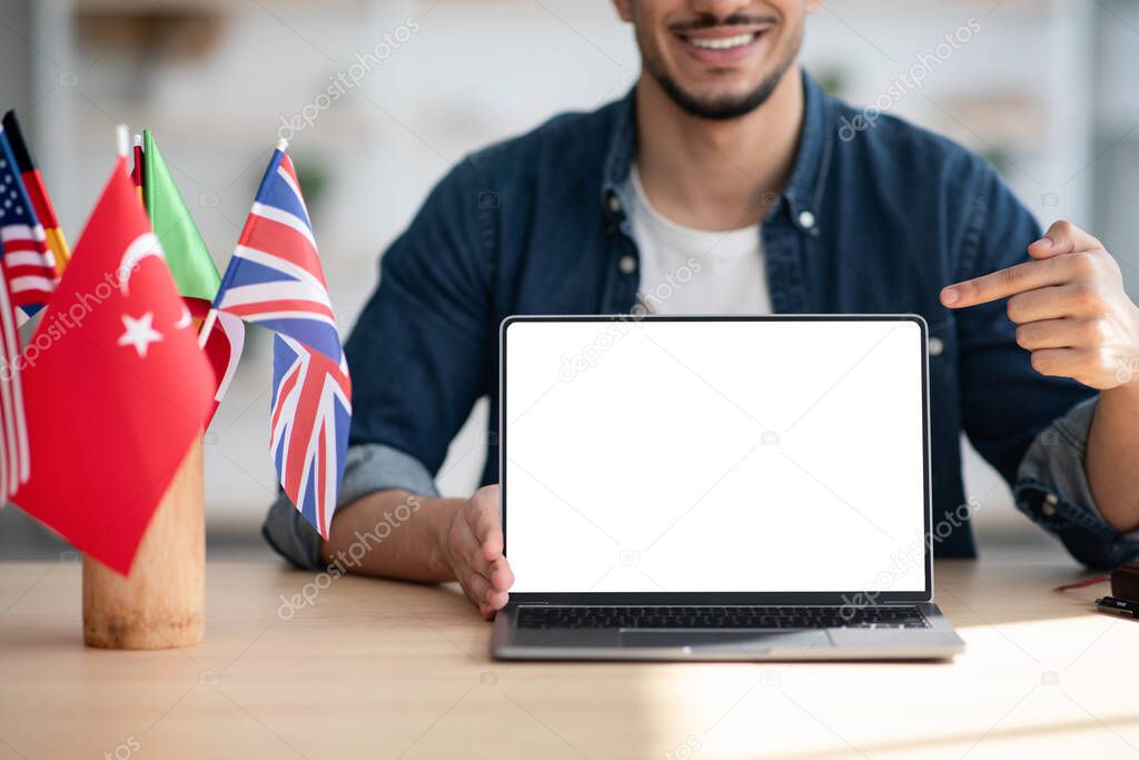 Cropped of arab man pointing at laptop with blank screen