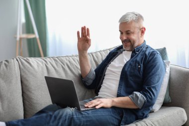 Mutlu yaşlı adam evden video konferansı yapıyor.