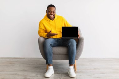 Gri Duvarın Üzerinde Oturan Afrikalı Amerikalı Laptop Ekranı Gösteriyor