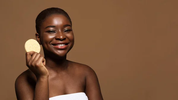 Concetto di cura della pelle. Carino africano signora holding cosmetico spugna per la pulizia del viso — Foto Stock