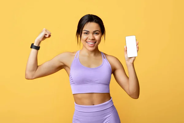 Sağlıklı yaşam tarzı ve spor uygulaması. Mutlu siyah kadın boş ekranlı akıllı telefon gösteriyor — Stok fotoğraf