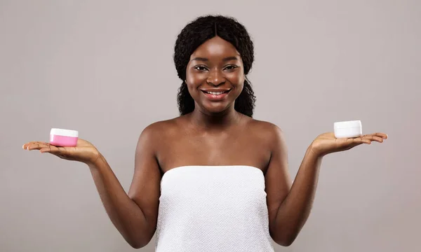 Melhores cosméticos para cuidados com o corpo. Bela senhora africana segurando frascos com creme — Fotografia de Stock