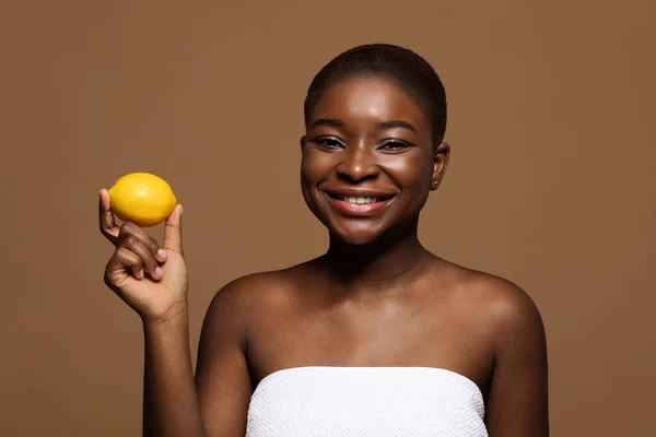Felice giovane donna africana con limone nelle mani in posa su sfondo marrone — Foto Stock