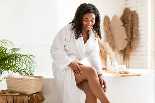 Negro femenino cuidado para el cuerpo tocando las piernas lisas en el baño —  Fotos de Stock