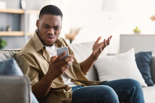 Ontevreden Afro-Amerikaanse man met behulp van mobiele telefoon met problemen thuis — Stockfoto