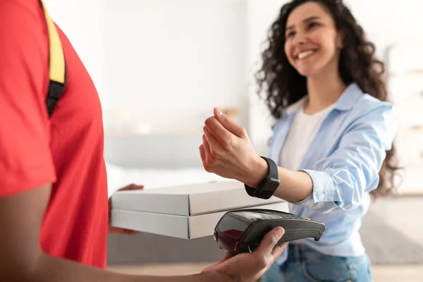 Livreur tenant boîte à pizza et terminal, femme payant avec smartwatch — Photo