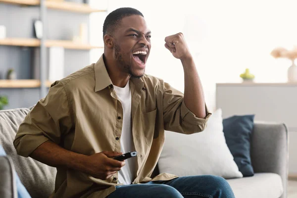 勝利を祝うテレビでスポーツを見て感情的なアフリカ人男性屋内 — ストック写真