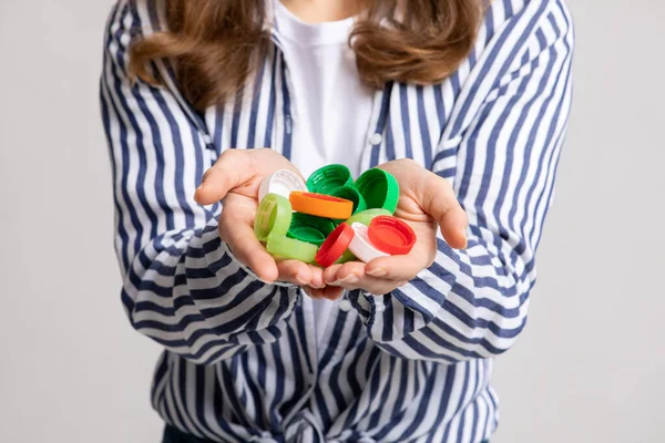 手にプラスチックボトルからカラフルな蓋の認識できない女性保持束 — ストック写真