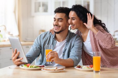 Mutfaktaki Dijital Tablet 'e video çağrısı yapan neşeli Arap eşler