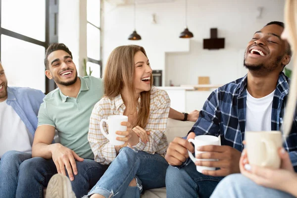 Grupo de amigos multirraciais felizes bebendo café na sala de estar, conversando, curtindo o tempo juntos — Fotografia de Stock