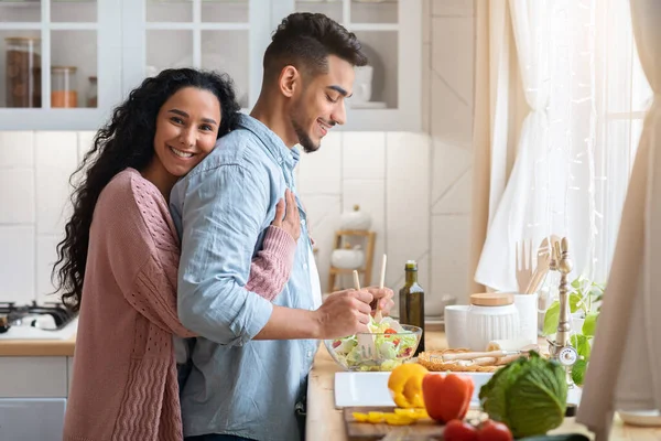 Πορτρέτο της αγαπημένης αραβικής συζύγου αγκαλιάζει το σύζυγο ενώ μαγειρεύουν μαζί στην κουζίνα — Φωτογραφία Αρχείου