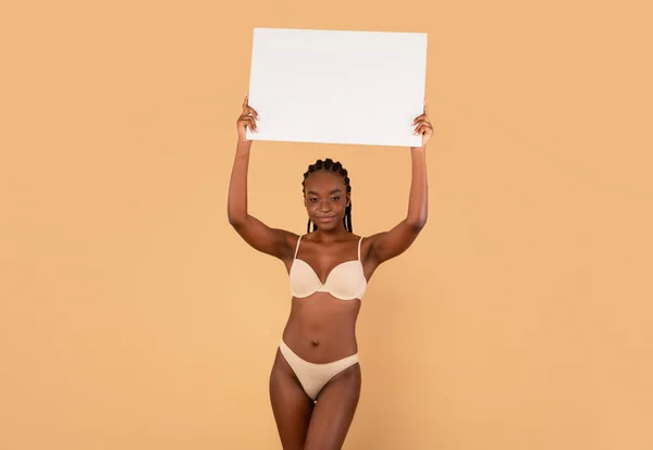 Motivasyon Bayrağı. Formda vücutlu siyah kadın. İç çamaşırı giyiyor. Beyaz pankart tutuyor. — Stok fotoğraf