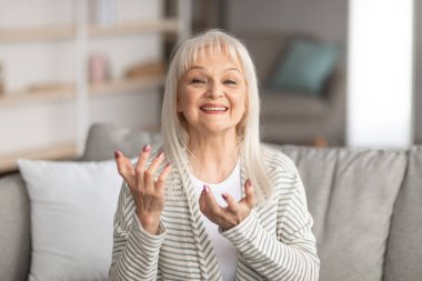 Olgun kadın kameraya konuşuyor ve gülümsüyor.