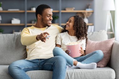 Sevimli siyah aile babası ve kızı birlikte film izliyorlar.