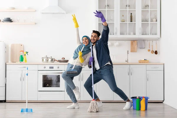 Funny muslim couple singing songs while cleaning kitchen, copy space — Stock Photo, Image