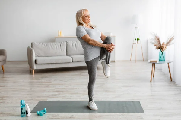 Mature woman exercising at home stretching leg