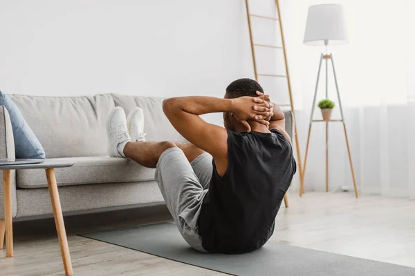 Negro chico haciendo abdominales crujidos ejercicio en el portátil en casa — Foto de Stock