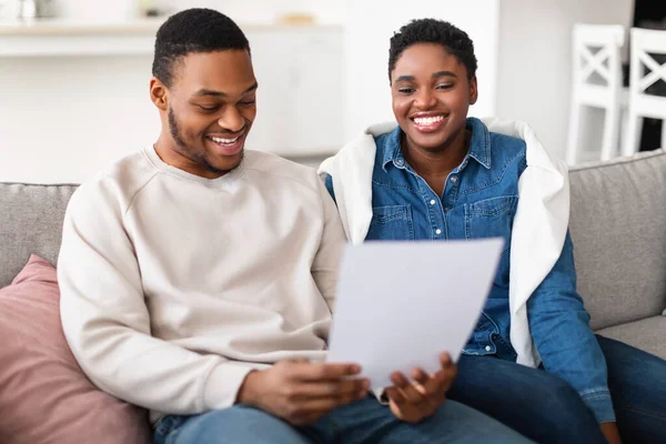 Lächelndes Afro-Paar liest Dokumentation zu Hause — Stockfoto
