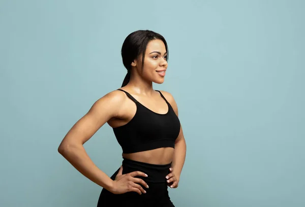 Buďte fit. Afričanky americká žena ve sportovním oblečení pózování a pohledu stranou na volné místo na modrém pozadí, studio shot — Stock fotografie