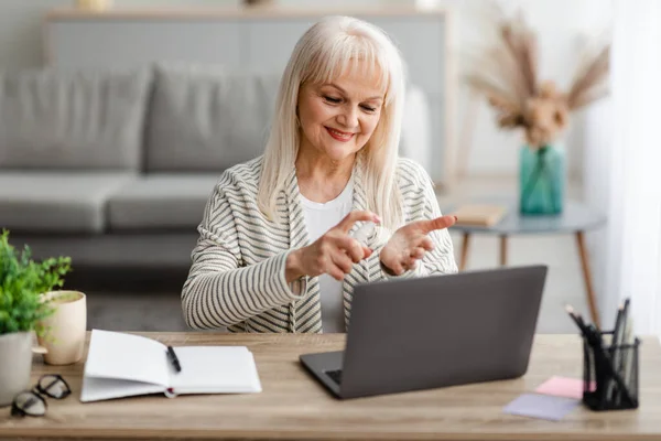 Glimlachende volwassen vrouw spraying sanitizer op de hand — Stockfoto