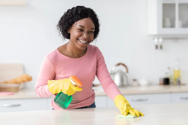 Sorrindo preto senhora limpeza de móveis de cozinha, espaço de cópia — Fotografia de Stock