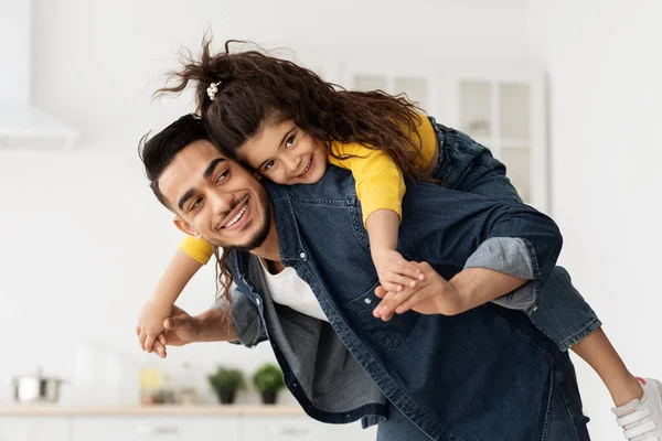 Alegre árabe papá con su linda hija en la espalda y riendo —  Fotos de Stock