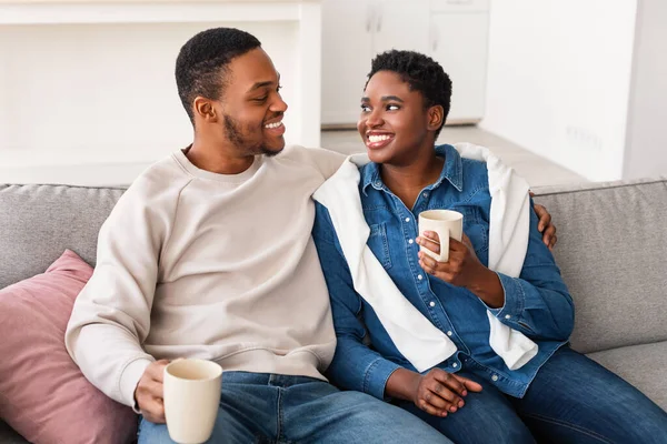 Pareja negra tomando café pasando tiempo juntos descansando en el sofá — Foto de Stock