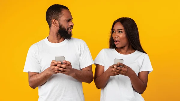 Confuso triste milenar casal afro-americano segurando seus telefones — Fotografia de Stock