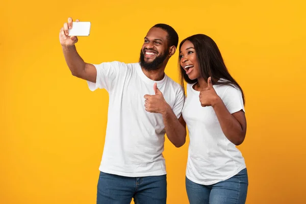 Mutlu siyah adam ve kadın selfie çekerken başparmak kaldırıyor. — Stok fotoğraf