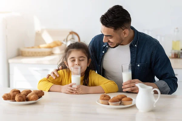 Roztomilé malé arabské dívka těší pití mléka při jídle s tatínkem — Stock fotografie