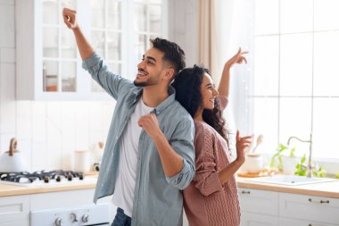 Pozitif genç Orta Doğulu çift, rahat mutfakta dans ediyor, birlikte eğleniyorlar.