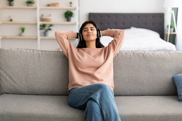 Mujer joven escuchando música usando auriculares — Foto de Stock