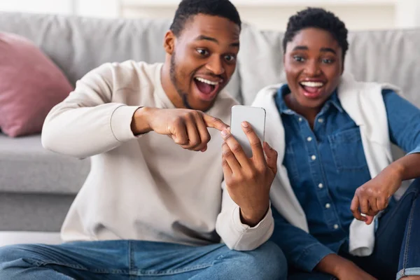 Schwarzes Paar mit Handy auf dem Boden sitzend — Stockfoto
