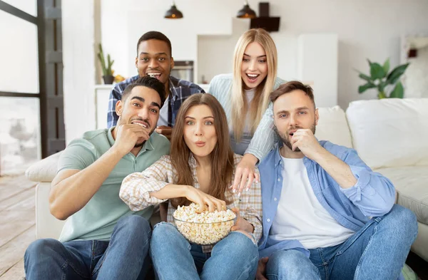 Bir grup çok ırklı arkadaş televizyon izliyor, patlamış mısır yiyor, evde birlikte eğleniyorlar. — Stok fotoğraf