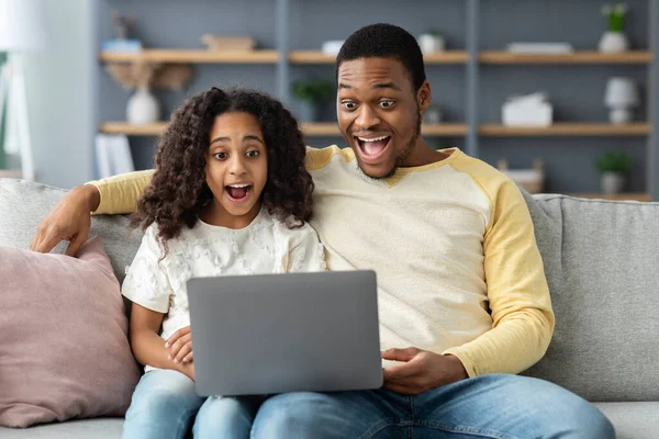 Impresionado papá negro y su hija usando la computadora en casa — Foto de Stock