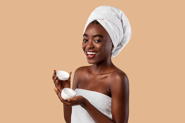 Linda jovem afro-americana segurando frasco creme rosto — Fotografia de Stock