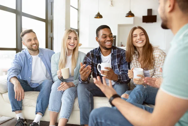 Diversos amigos milenares conversando e rindo juntos, bebendo chá ou café em casa — Fotografia de Stock