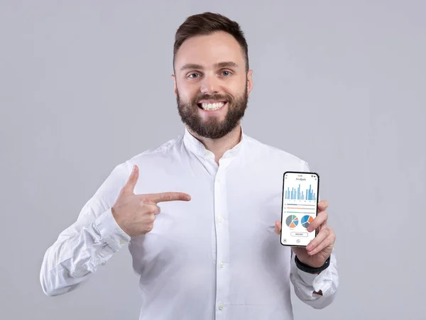 Glücklicher Geschäftsmann hält Telefon mit Analyse-App auf dem Bildschirm — Stockfoto
