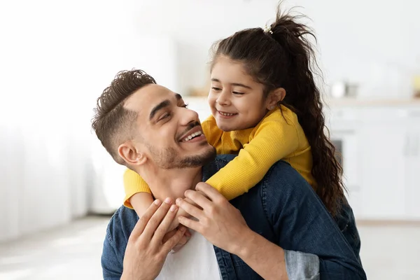 Bonito feliz pouco árabe menina abraçando seu pai a partir de volta e rindo — Fotografia de Stock