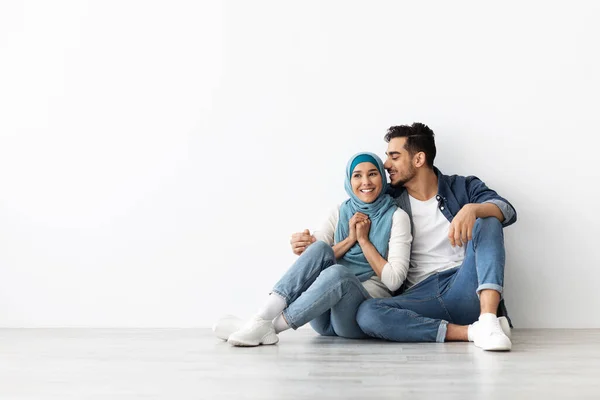 Donna gioiosa in hijab seduta sul pavimento con suo marito — Foto Stock