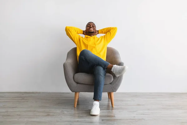 Chico afroamericano relajante sentado en sillón cómodo, fondo gris —  Fotos de Stock