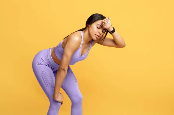 Fim da corrida. Africano americano mulher em sportswear cansado de treinamento e descansando em fundo amarelo, espaço livre — Fotografia de Stock