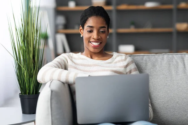 Millennial Black Lady siedzi na kanapie z laptopem w domu — Zdjęcie stockowe