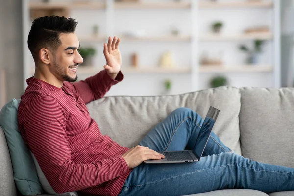 Hombre árabe alegre tener videollamada desde casa, utilizando el ordenador portátil — Foto de Stock