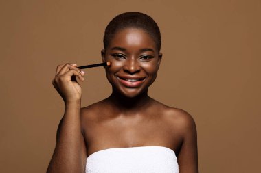 Temel Makyaj. Gülümseyen Afrikalı Kadın Makyaj fırçasıyla Yüze Dokunuyor