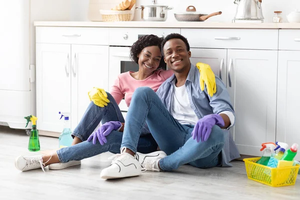 Cansado casal negro sentado na cozinha, abraçando e sorrindo — Fotografia de Stock