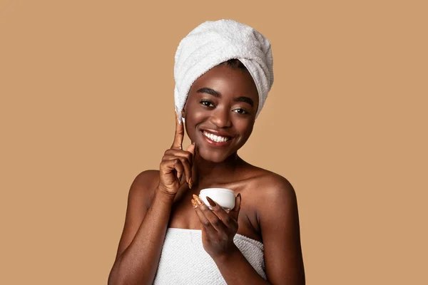美しい若いですアフリカ系アメリカ人女性適用フェイスクリームからjar — ストック写真