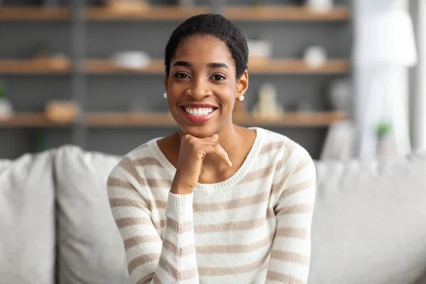 Портрет счастливой чернокожей женщины на диване в домашнем интерьере — стоковое фото