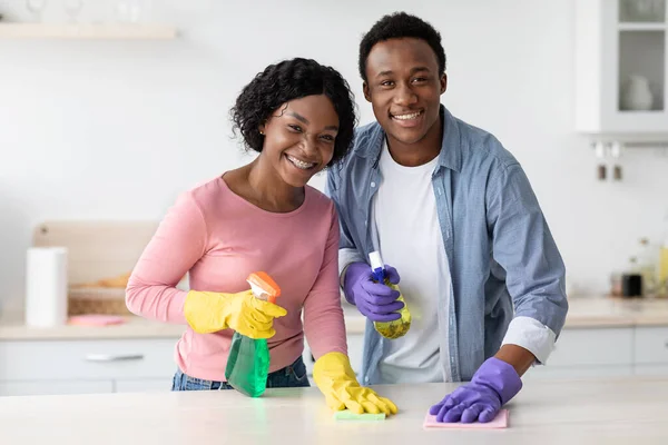 Alegre casal preto limpeza cozinha e sorrindo para a câmera — Fotografia de Stock